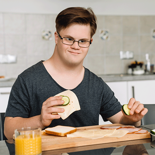 Young man preparing food in the kitchen, symbolising daily living independence and continence support services in Ipswich.