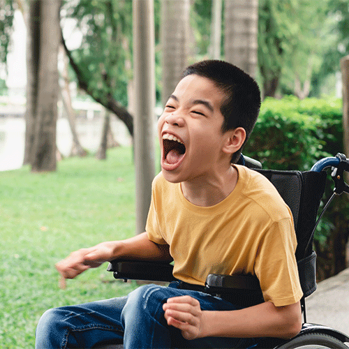 Young boy using a wheelchair enjoying time outdoors in a park, representing inclusive disability and continence support services